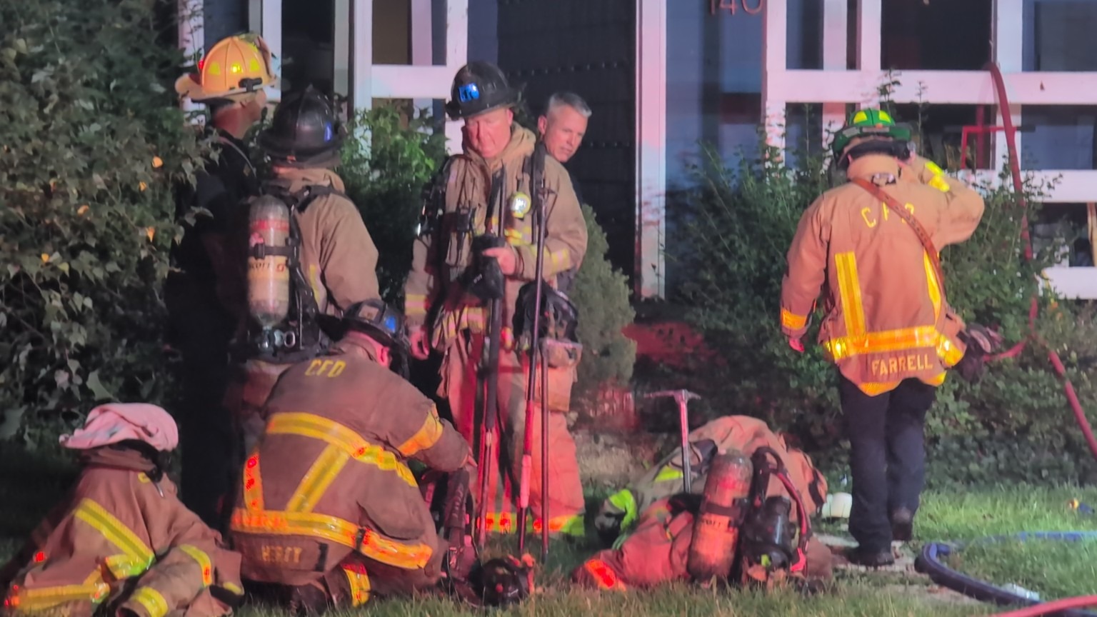 Firefighters gathered beside a building at night