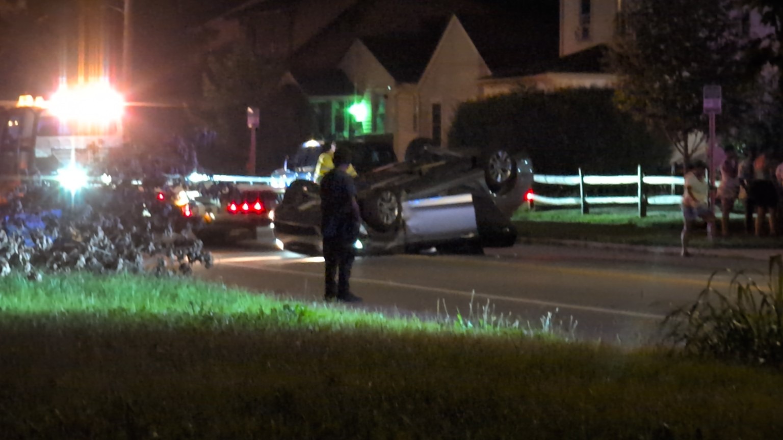 A vehicle on its side with responders nearby at night