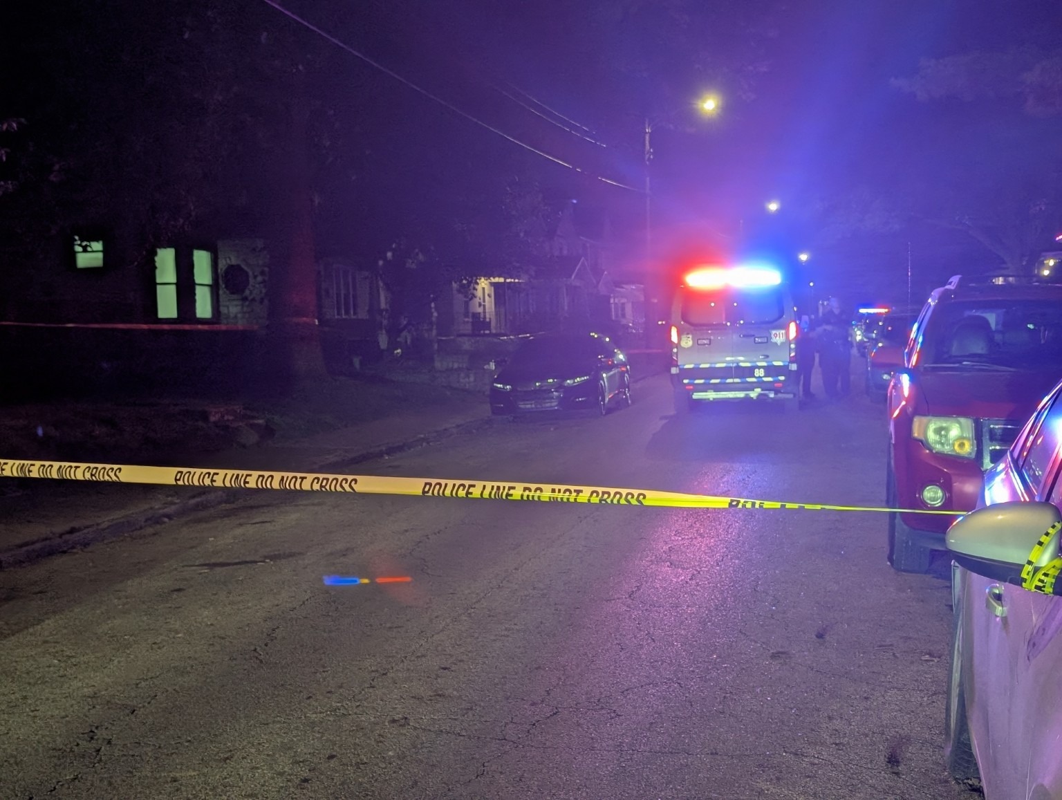 Emergency vehicles and police tape on a city street after dark